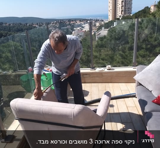 אדם מנקה ספה עם שואב אבק במרפסת